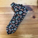 1. Corbata de seda con estampado de paisley en colores azul, rojo y amarillo sobre fondo negro.