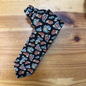 1. Corbata de seda con estampado de paisley en colores azul, rojo y amarillo sobre fondo negro.