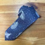 Cinta de moño azul con plumas y puntos blancos, ideal para accesorios y moda artesanal.