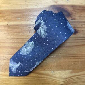 Cinta de moño azul con plumas y puntos blancos, ideal para accesorios y moda artesanal.