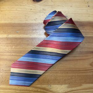 Cinturón de mujer con diseño de rayas en tonos rojos, azules y dorados, ideal para complementos elegantes.