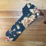 1. Corbata de seda con estampado floral en tonos crema y verde sobre fondo azul.