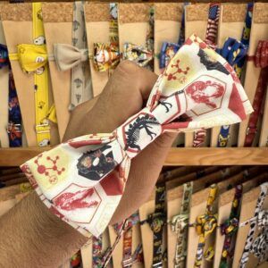 1. Corbata de tela con diseño de dinosaurios y motivos científicos en colores rojo y beige.