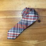 Corbata de tartán azul, rojo y crema sobre mesa de madera.
