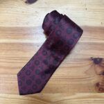 Corbata burdeos con logotipos de marcas de lujo, elegante y de diseño exclusivo.