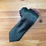 Corbata de seda verde con patrón de triángulos, estilo moderno y elegante.