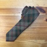 Corbata de lana con estampado de tartán en tonos verde, gris y rojo, ideal para looks clásicos y elegantes.
