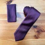 Corbata color burdeos con textura satinada y foulard a juego, elegante y perfecta para ocasiones formales.