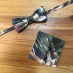 Corbata y tarjetero de tela con estampado floral en tonos verdes y blancos.
