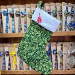 Botín de Navidad con diseño de ramas de pino y borde blanco, ideal para decorar tus fiestas navideñas.