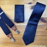 Corbata azul marino con acabados elegantes y accesorios a juego.