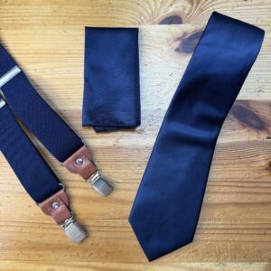 Corbata azul marino con acabados elegantes y accesorios a juego.