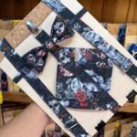 Colgante de tela con diseño de calaveras y rosas en colores oscuros, ideal para accesorios de moda alternativas.