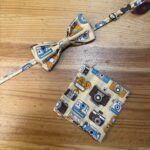Cinta y monedero con estampado de cámaras fotográficas vintage en tonos beige, azul y negro. Complementos únicos para amantes de la fotografía.