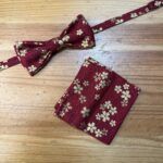 Corbata y pañuelo de seda con diseño floral en rojo y dorado para ocasiones elegantes.