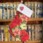 Bota navideña con estampado de flores de poinsettia y ribete de felpa blanca, ideal para la decoración de Navidad.