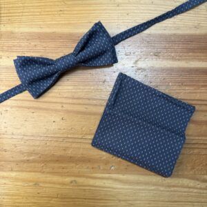 Corbatín y pañuelo elegantes en tela azul con pequeños puntos blancos para ocasiones formales.
