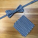 Corbata de moño y pañuelo a juego con estampado a puntos blancos sobre fondo azul marino.