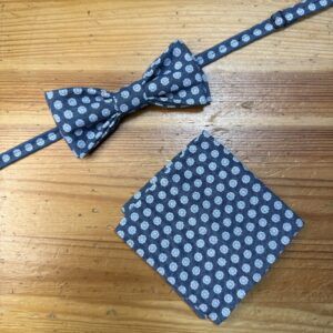 Corbata de moño y pañuelo a juego con estampado a puntos blancos sobre fondo azul marino.
