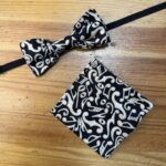 Corbata y bandana negras con patrón musical en blanco, accesorios elegantes y modernos.