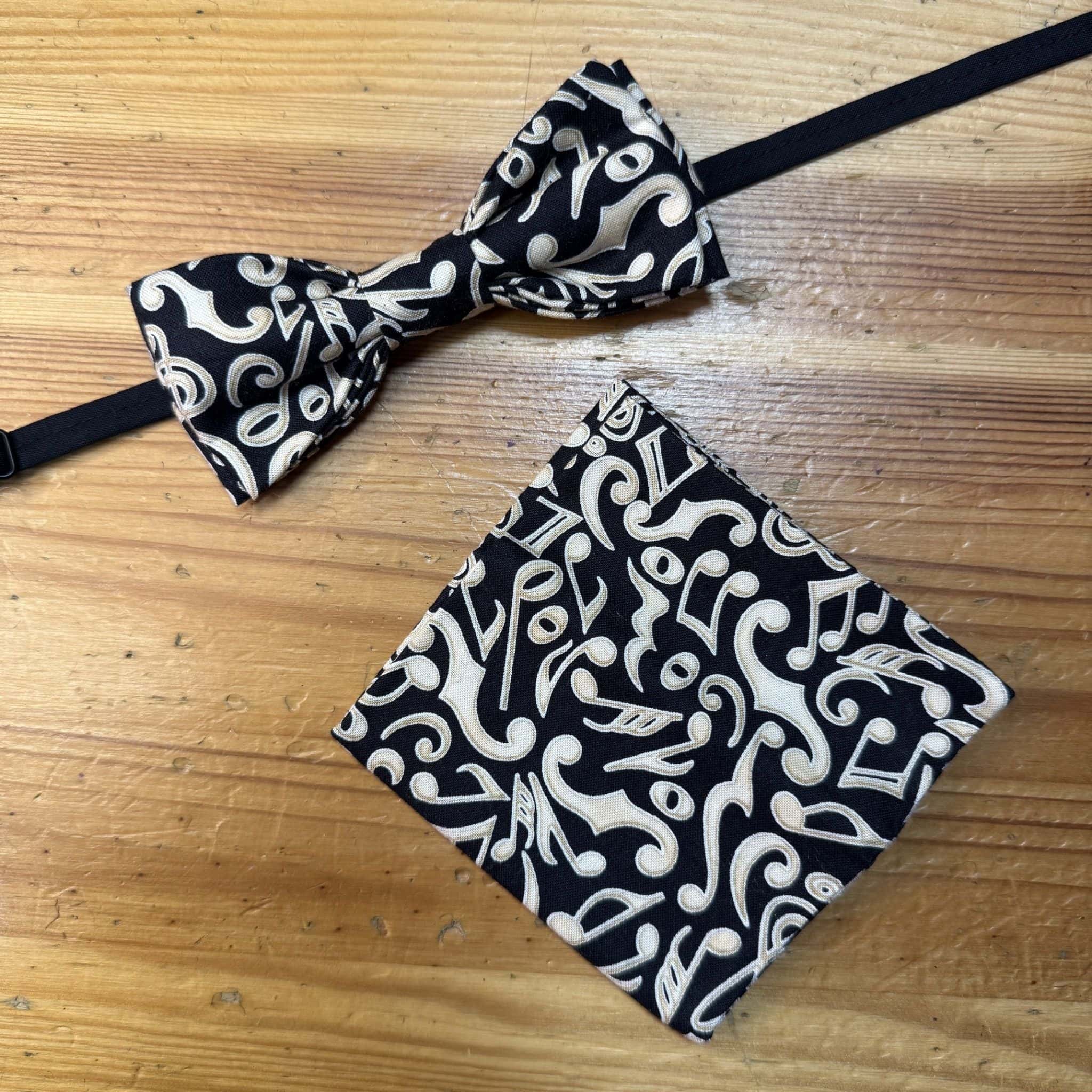 Corbata y bandana negras con patrón musical en blanco, accesorios elegantes y modernos.