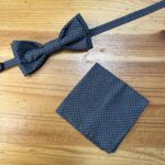 Corbata y pañuelo a juego en tela negra con patrón de diamantes, ideales para ocasiones especiales.