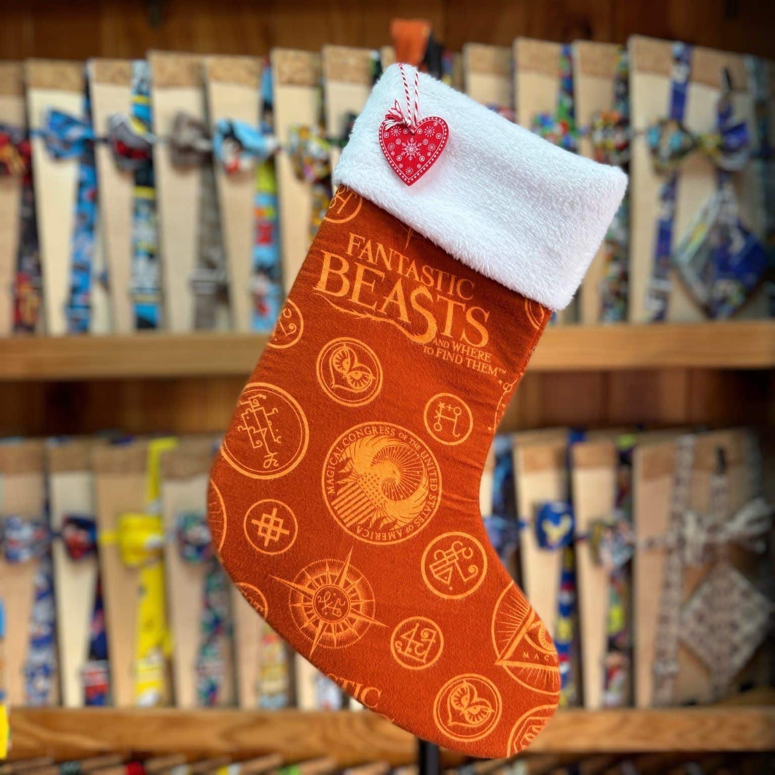 Calcetín de Navidad de "Fabulous Beasts" con diseño de símbolos mágicos y letras en tonos anaranjados, con acabado blanco en la parte superior.
