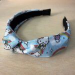 Colorido diadema con diseño de Hello Kitty, arcoíris y nubes, perfecto para accesorios infantiles y moda.