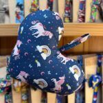 Colorido guante infantil con diseños de unicornios, arcoíris y nubes en fondo azul oscuro.
