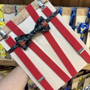 Corbata de regalo con rayas rojas y una pajarita de estampado navideño en madera clara.