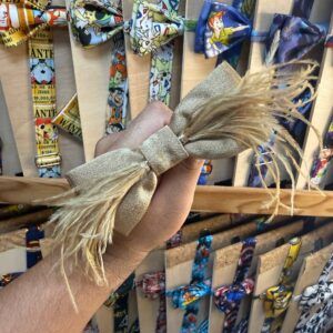 1. Lazo decorativo con tela y plumas en tonos dorados para accesorios y regalos.