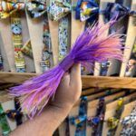 Colorido lazo de flecos en tonos lilas y rosados, perfecto para accesorios y decoración de eventos.